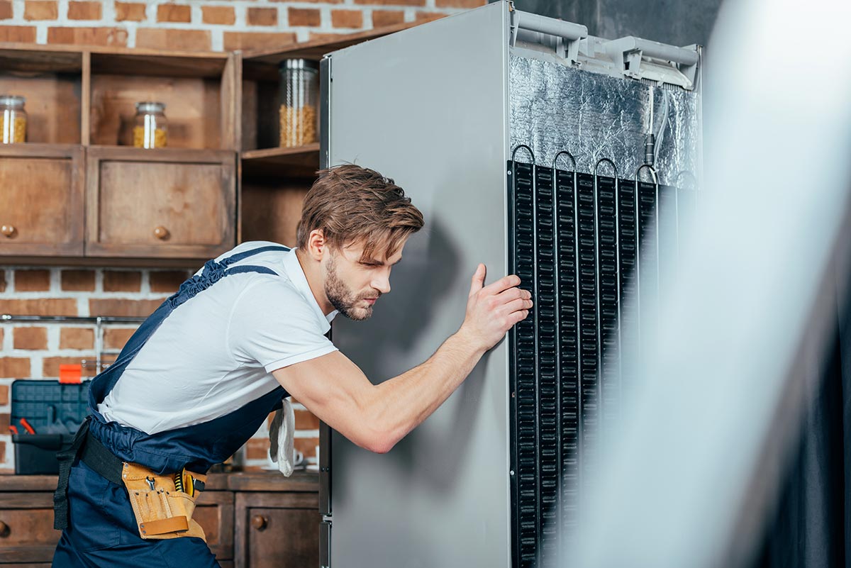 young-repairman-in-protective-workwear-moving-refr-resize.jpg